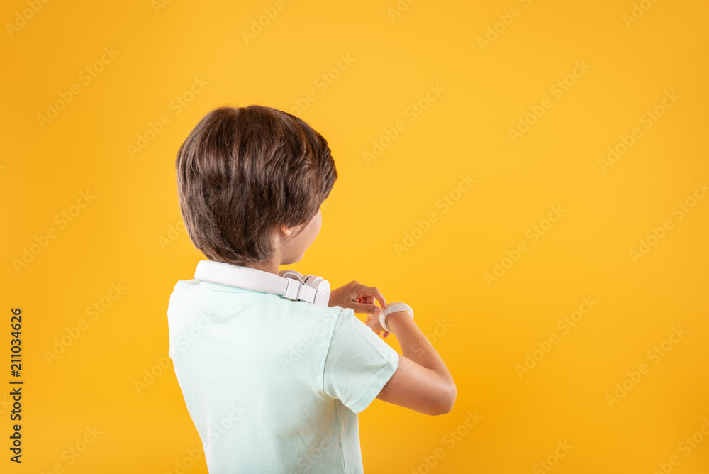 So clever. Adorable dark-haired boy thinking and looking at his watch So clever. Adorable dark-haired boy thinking and looking at his watch