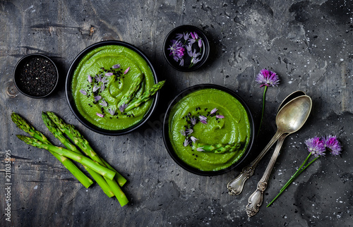 Homemade green spring asparagus cream soup decorated with black sesame seeds and edible chives flowers photo