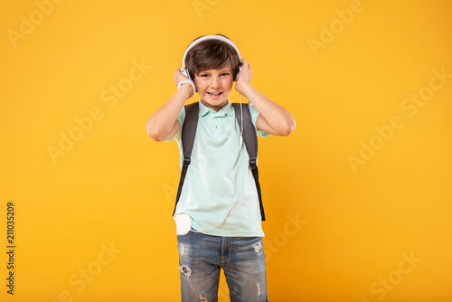 My hobby. Cheerful athletic boy wearing his schoolbag and listening to music
