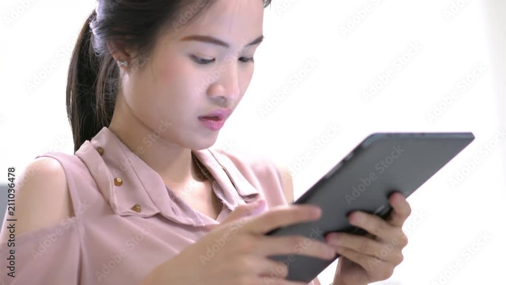Asian woman lookinng tablet computer at home. Lifestyle of Student girl learning online at home. concept of education and technology. Asian woman lookinng tablet computer at home. Lifestyle of Student girl learning online at home. concept of education and technology.