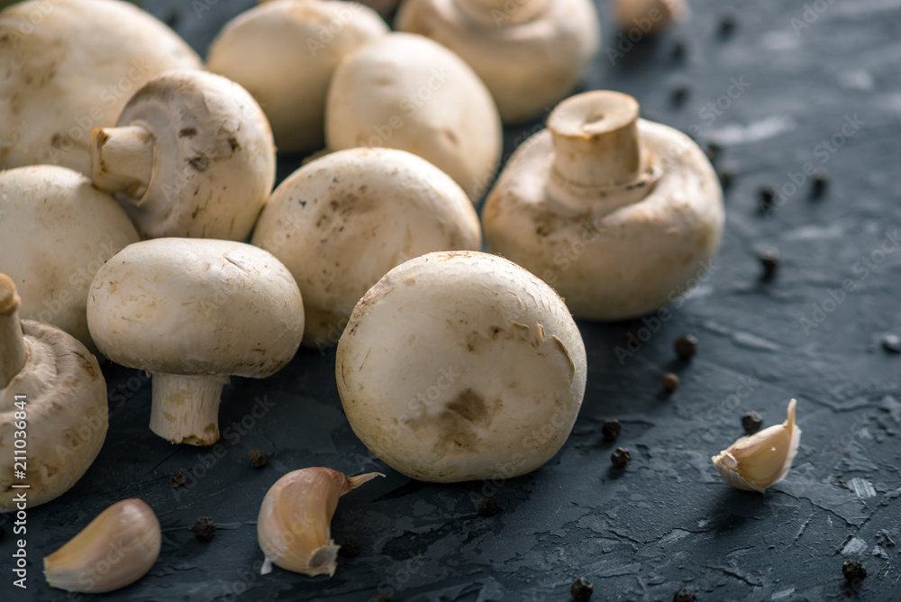 Fresh white Champions, spices and ingredients on the dark kitchen table. Concept of cooking mushroom dishes Fresh white Champions, spices and ingredients on the dark kitchen table. Concept of cooking mushroom dishes
