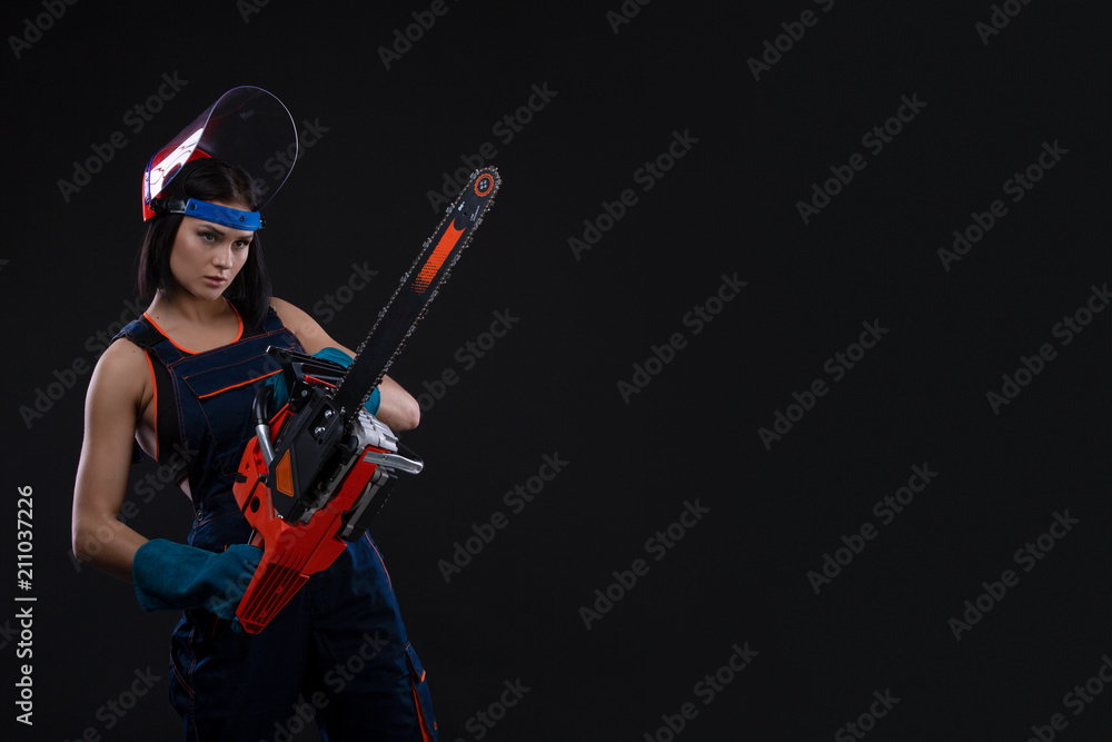 beautiful hot sexy woman hold a chainsaw over black background beautiful hot sexy woman hold a chainsaw over black background