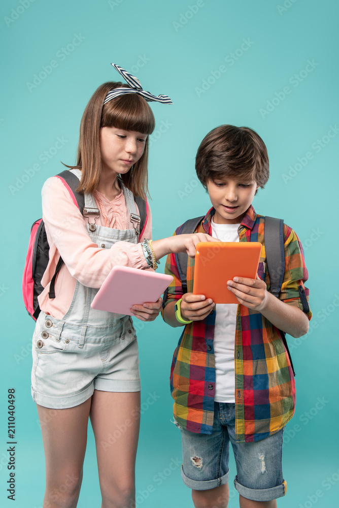 IT. Determined pretty girl holding her tablet and fixing her friends tablet IT. Determined pretty girl holding her tablet and fixing her friends tablet
