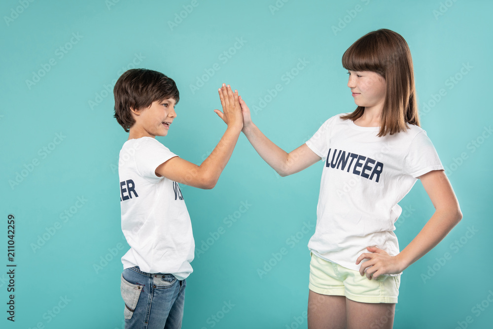 Well done. Cheerful young volunteers smiling and giving a high-five Well done. Cheerful young volunteers smiling and giving a high-five