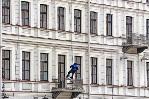 An industrial climber hanging on a rope and washing the windows of a house