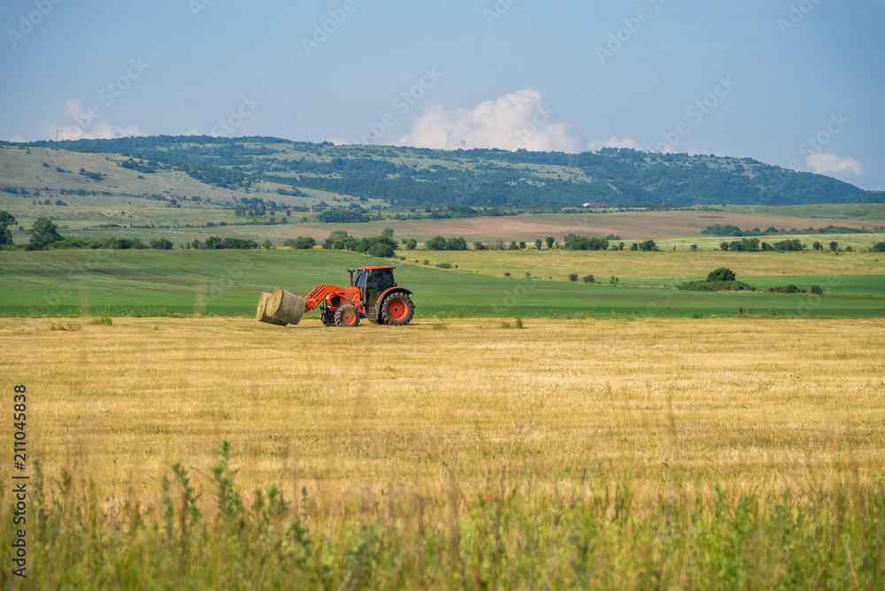Tractor lifting hay bale on barrow. Tractor lifting hay bale on barrow.