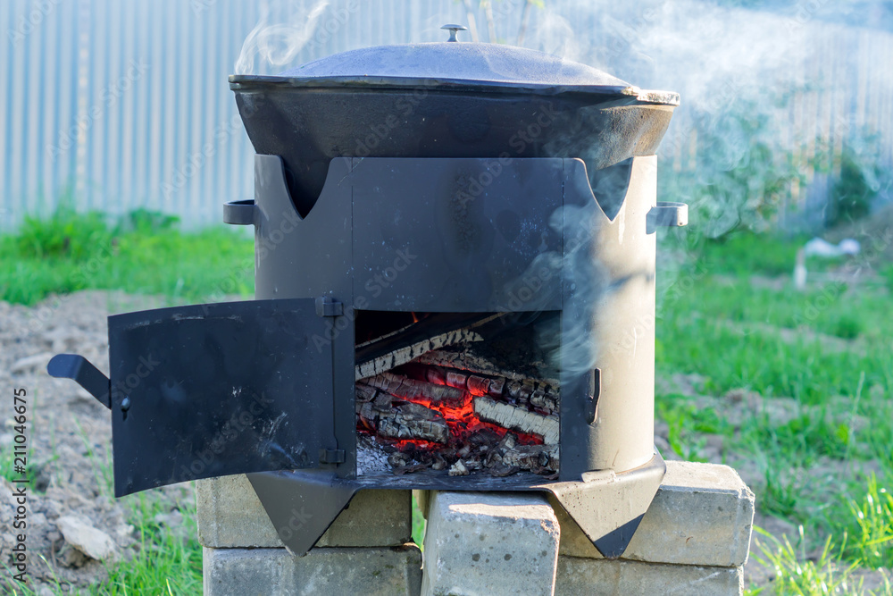 Big metal cauldron pot on movable stove outdoors Big metal cauldron pot on movable stove outdoors