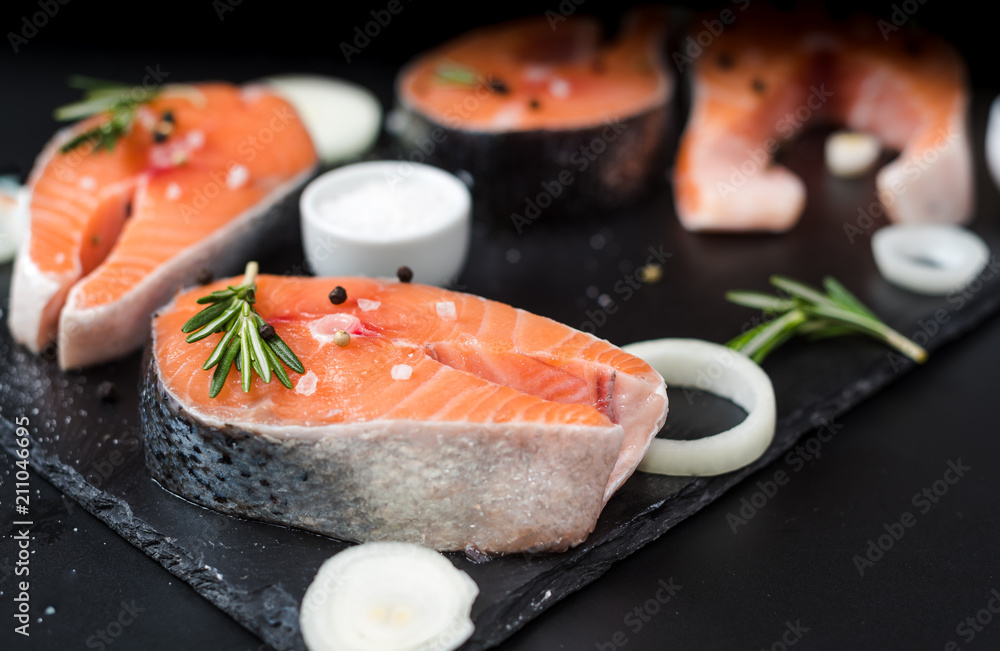 Raw salmon steak on black stone, prepared for cooking Raw salmon steak on black stone, prepared for cooking