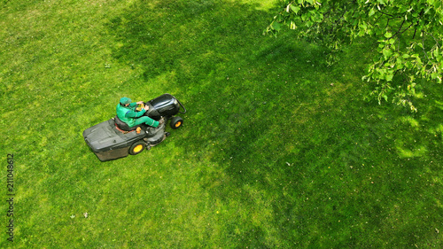 Grass cutting in the park. Lawnmower and gardener. photo