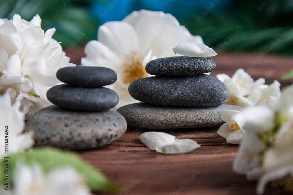 Fototapeta premium Pyramids of gray zen stones with beautiful fresh white flowers. Concept of harmony, balance and meditation, spa, massage, relax