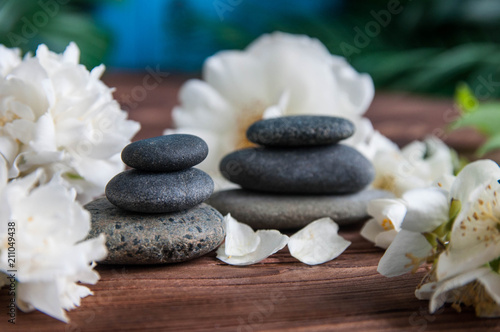 Pyramids of gray zen stones with beautiful fresh white flowers and Buddha statue. Concept of harmony, balance and meditation, spa, massage, relax