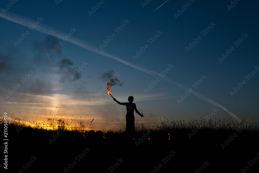 A man with a torch at sunset. Fire show and a lot of the bright sparks in the night