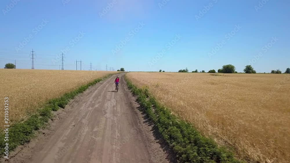 The girl is riding a bicycle on the road in the fields. 4K The girl is riding a bicycle on the road in the fields. 4K