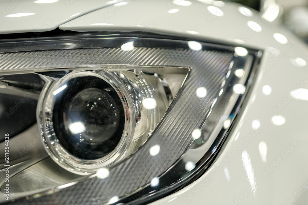 Luxury white car headlight close-up. Concept of expensive, sports auto.  The concept of tuning. Headlight of  modern prestigious car.