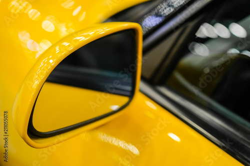 Close-up the side mirror of a yellow sports car. Rear-view mirror.