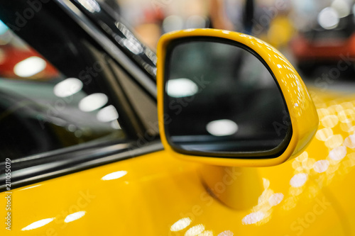 Close-up the side mirror of a yellow sports car. Rear-view mirror.