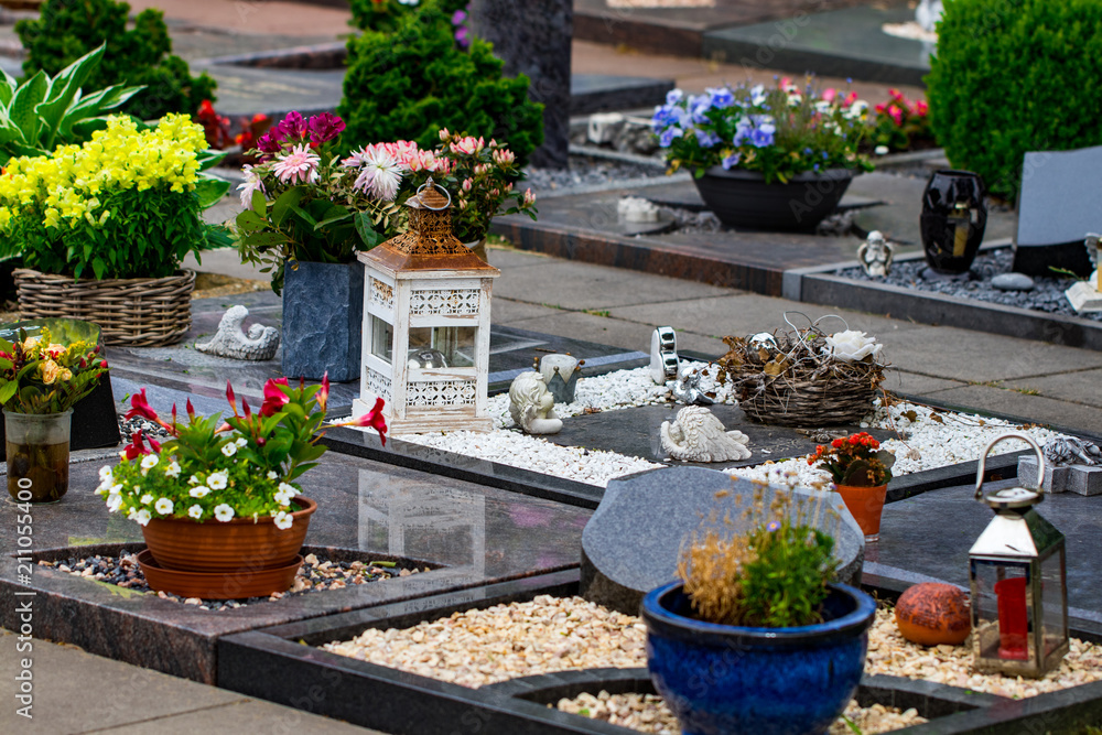 Headstones in a cemetery with many different flowers