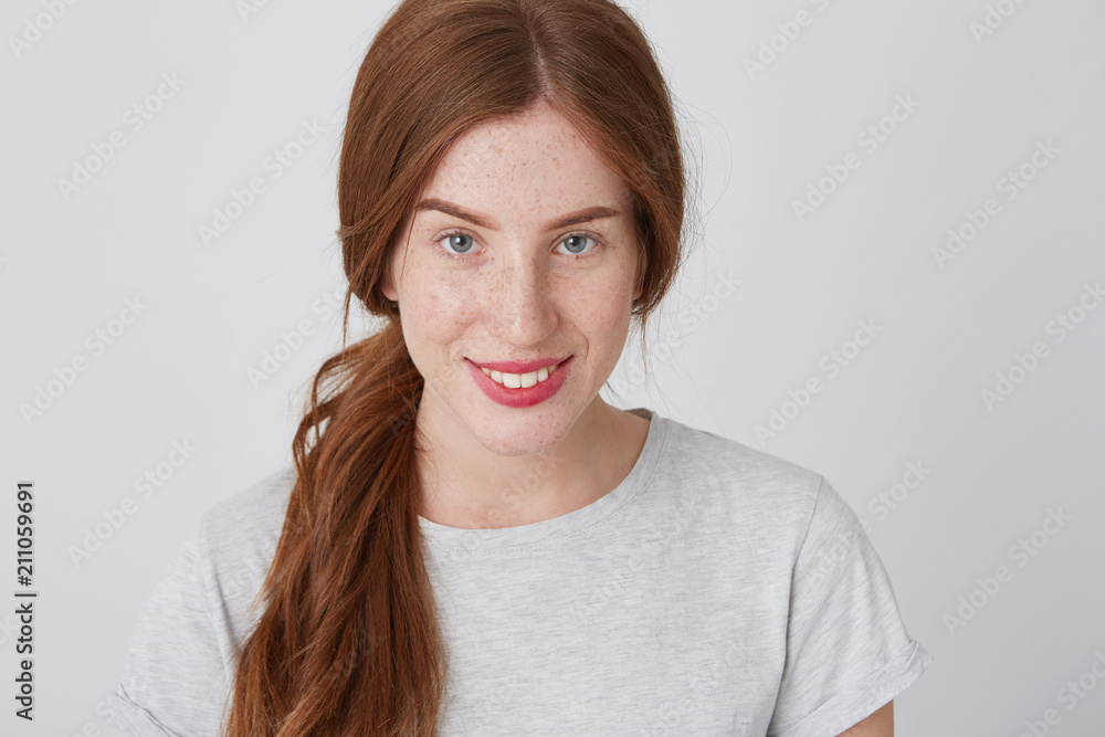 Closeup of cheerful pretty redhead young woman with freckles looking at camera and smiling isolated over white background Closeup of cheerful pretty redhead young woman with freckles looking at camera and smiling isolated over white background