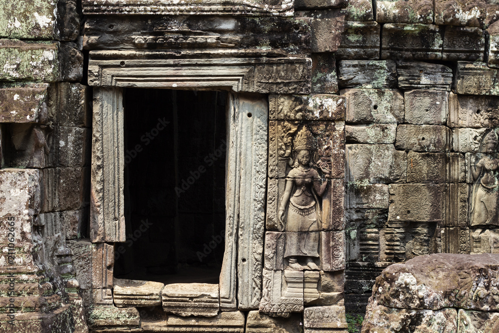 Ancient stone bas-relief of Banteay Kdei temple, Angkor Wat, Cambodia. Ancient temple door with stone carving.