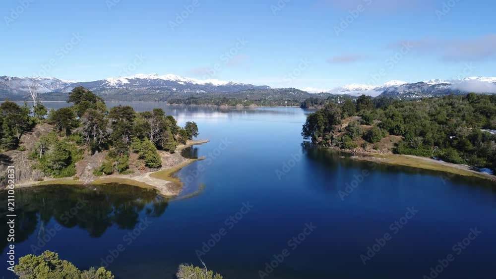 Aerial drone scene of Alumine lake, in Villa Pehuenia, Moquehue, Neuquen, Patagonia Argentina. Camera moving forward in between islands. Mountains with snow and houses on the background. Aerial drone scene of Alumine lake, in Villa Pehuenia, Moquehue, Neuquen, Patagonia Argentina. Camera moving forward in between islands. Mountains with snow and houses on the background.