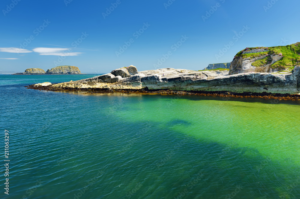 Obraz premium Vivid emerald-green water at Ballintoy harbour along the Causeway Coast in County Antrim, Northern Ireland.