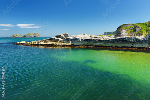 Vivid emerald-green water at Ballintoy harbour along the Causeway Coast in County Antrim, Northern Ireland.
