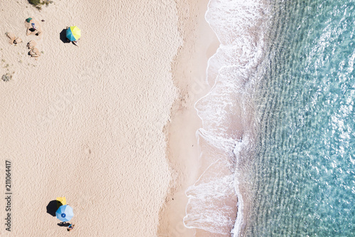 Aerial view of amazing turquoise sea with two coloured umbrellas. Beautiful sunny summer day in Sardinia, Mediterranean sea, Italy..