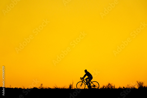 Silhouette of cyclist with friend in motion on the background of beautiful sunset © ณัฐวุฒิ เงินสันเทียะ