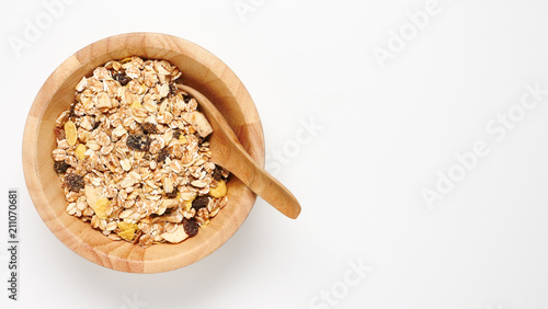Top view of oatmeal flakes in wooden bowl on white background. copy space