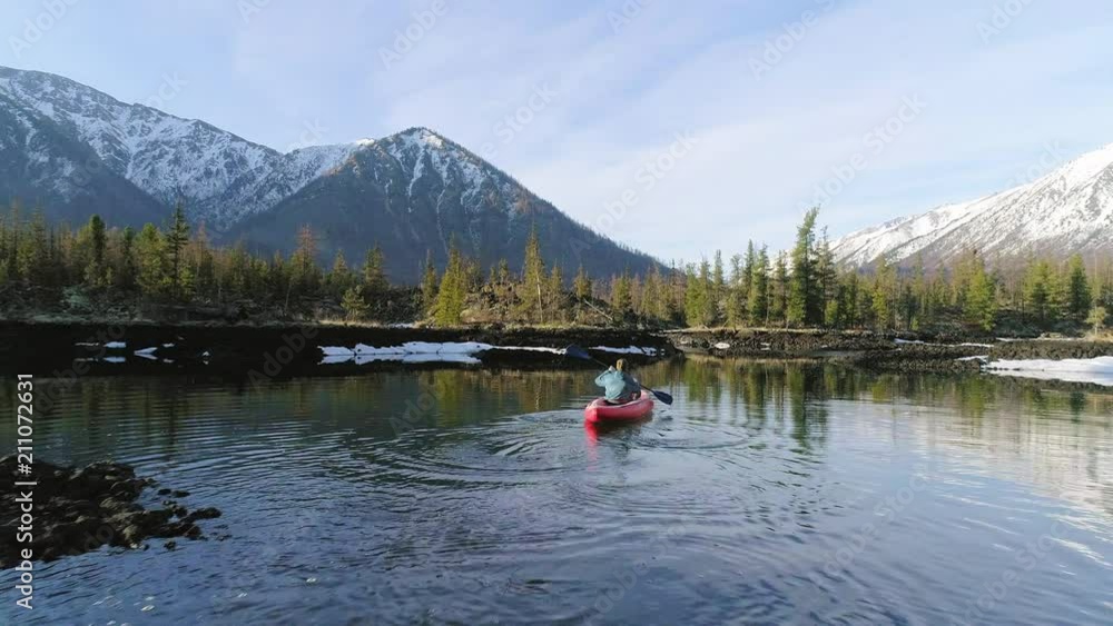 tourist sailing on a canoe in lake towards mountains in valley. aerial. tourist sailing on a canoe in lake towards mountains in valley. aerial.