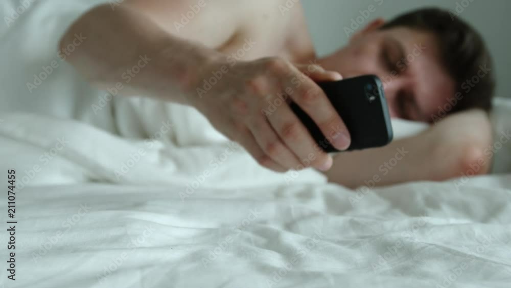 Young adult man sleeps, wakes up and talks by phone Young adult man sleeps, wakes up and talks by phone