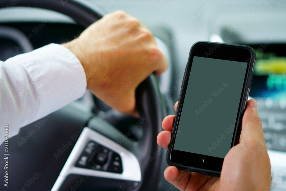 Don't text and drive ! A man is texting with a finger while a car is arriving in front. focus on the finger, focus on telephone, focus on the car coming. Don't text and drive ! A man is texting with a finger while a car is arriving in front. focus on the finger, focus on telephone, focus on the car coming.
