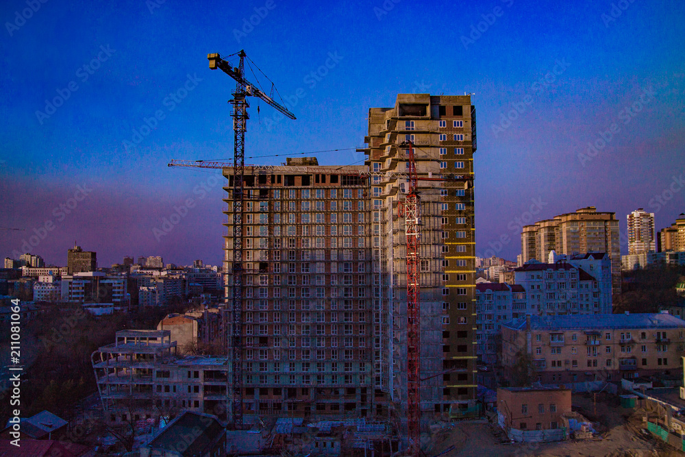 crane near a tall building on a constructin site in the city on bluesky background