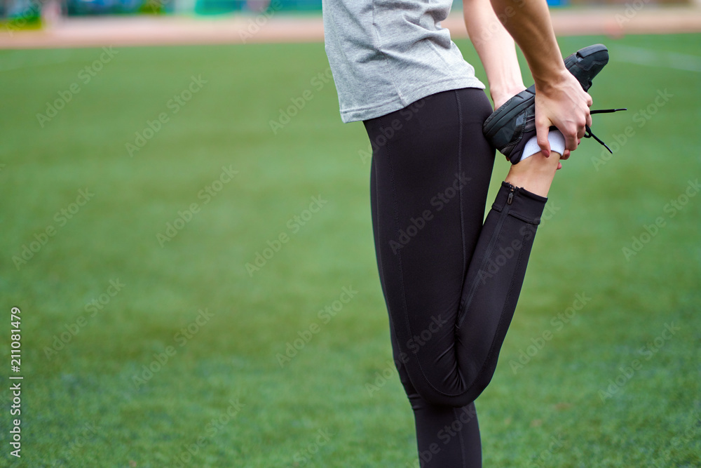 young fitness woman runner stretching legs before run on grass young fitness woman runner stretching legs before run on grass