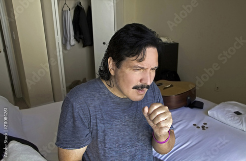 Man sitting on bed coughing photo