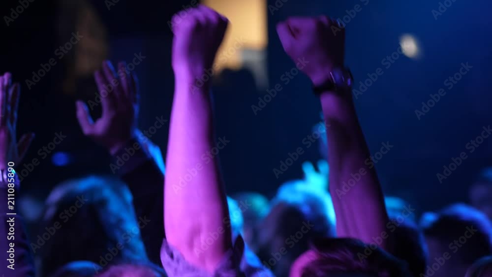 Jubilant cheering crowd of young people dance jump and raise hands on free music concert