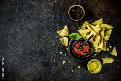 Mexican food, nachos snack with salsa and sauces on dark rusty background top view copy space