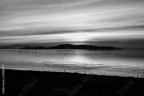 A shoot of a sunset over a lake, with many diagonal lines created by the clouds and the coastline