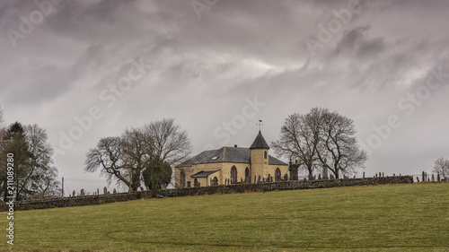 A small parish church isolated in a Scottish landscape with a stormy sky