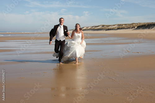 bride and groom running on the sand at sea beach summer