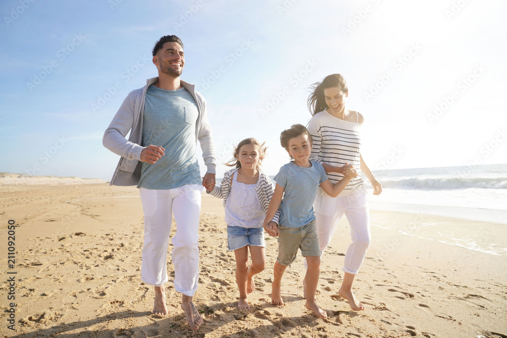 Family running on sandy beach at sunset