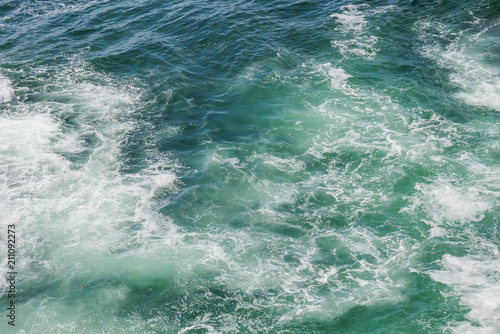 View of foam in green blue water during windy weather, beautiful ocean background