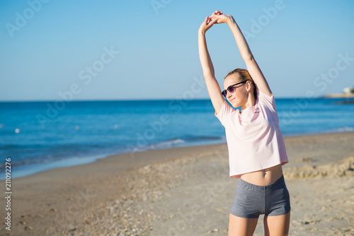 Young attractive woman doing morning exercises on the beach