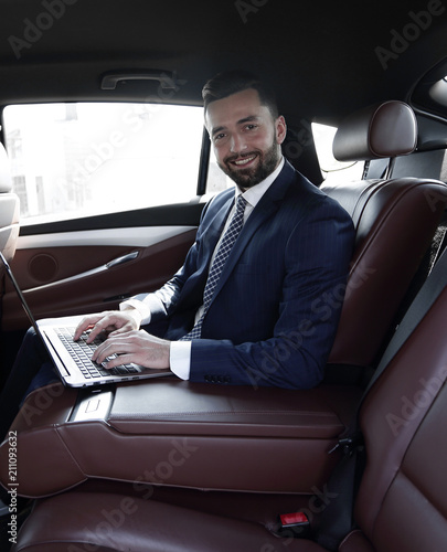 smiling businessman sitting in the back seat of a prestigious car © ASDF