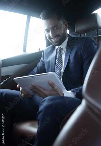 businessman with a digital tablet sitting in the back seat of a car © ASDF