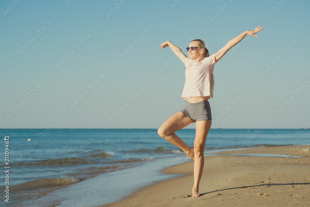 Young woman doing exercises on the beach in the morning. Toned Young woman doing exercises on the beach in the morning. Toned