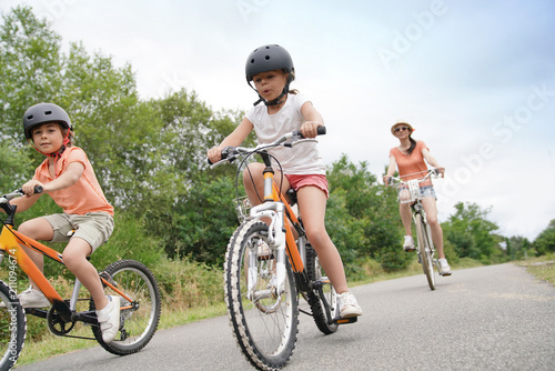 Obraz na plátně Kids with parents riding bikes in countryside