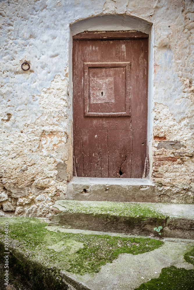 Old wooden door, moss-covered steps and stone eroded wall. Front door Old wooden door, moss-covered steps and stone eroded wall. Front door