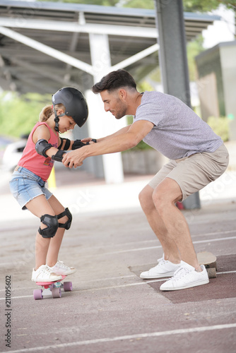 Young girl with dad learning how to skate