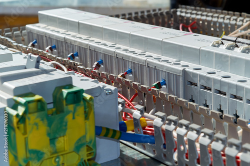 Modern modular contactors and circuit breakers with electrical wires connected to them. Assembly of the electric Cabinet in the workplace. The wires are laid in perforated cable channels.